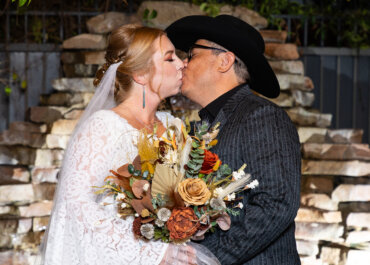 Bride and groom kissing with a hand-tied bouquet featuring dried flowers, celebrating their Las Vegas gazebo wedding at Lakeside Weddings & Events.