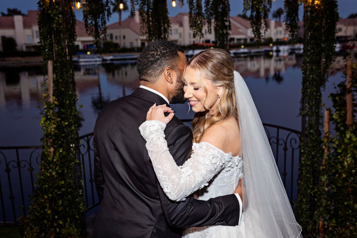 Bride and groom embracing at sunset by a lakeside venue